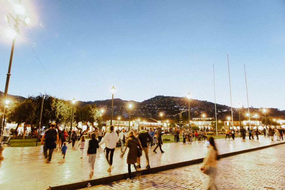 A bustling scene at the Plaza de Armas in Cusco, Peru, during twilight time.