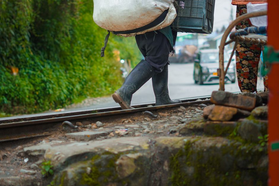 A person walking along railway tracks carrying bundles in Darjeeling, India.