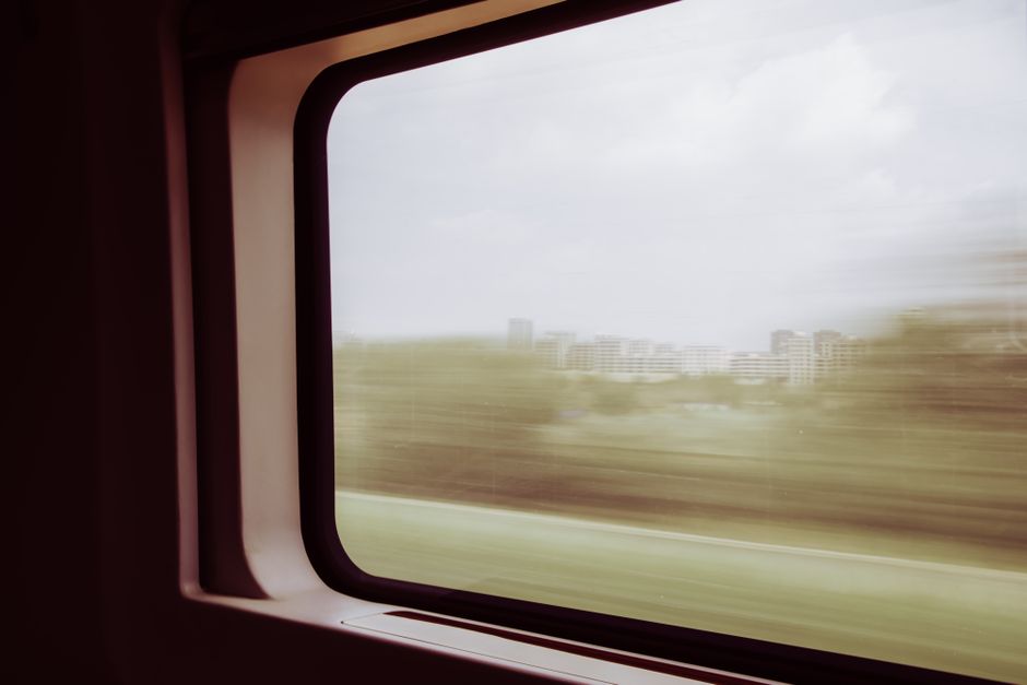 Blurred cityscape through train window, showing urban landscape in motion.