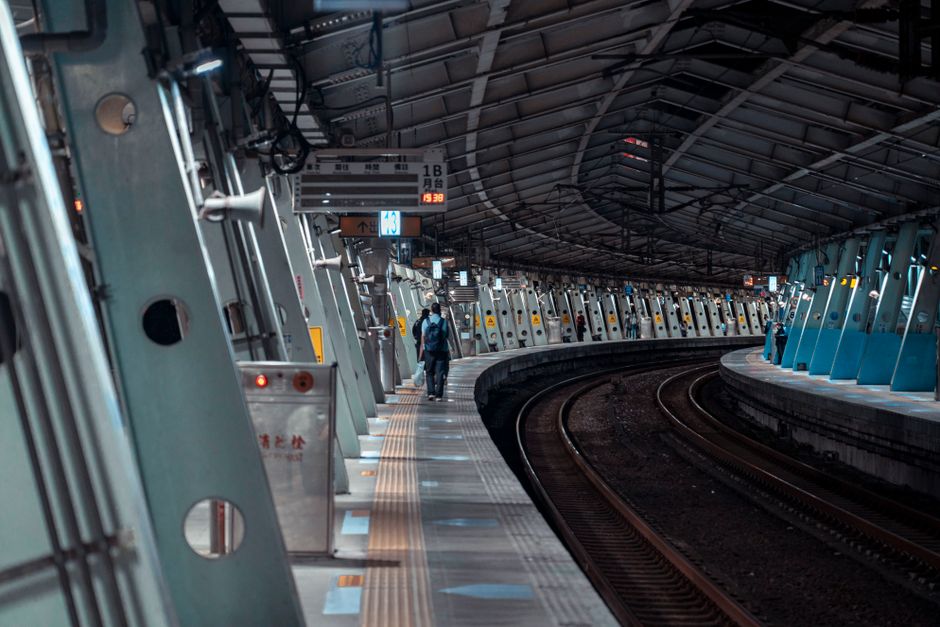 Urban subway station at night with curved tracks, showing commuters and modern architecture.