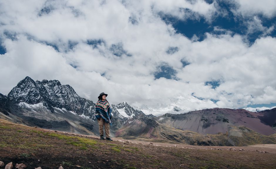 A lone traveler stands before the majestic snow-capped Ausangate in Peru's mountain range.