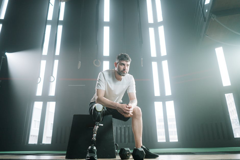 Male athlete with prosthetic leg sitting in a sunlit gym, embodying strength and determination.