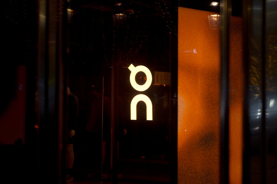 Glowing store sign with reflective glass surface captured in an urban setting at night.