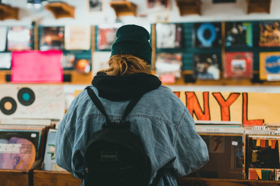 Adult woman in a beanie browsing vinyl records in a cozy music store.