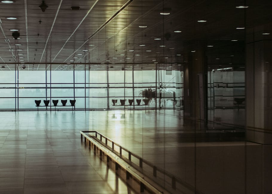 A calm and empty airport terminal in Singapore with a reflective glass facade and soft lighting.