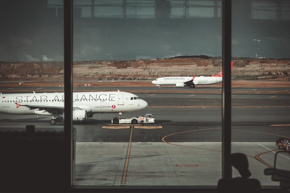 A view through airport windows showing airliners on the runway, creating a travel ambiance.
