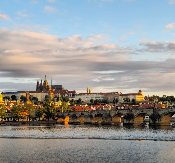 Scenic view of Prague Castle and Charles Bridge over the Vltava River at sunset.