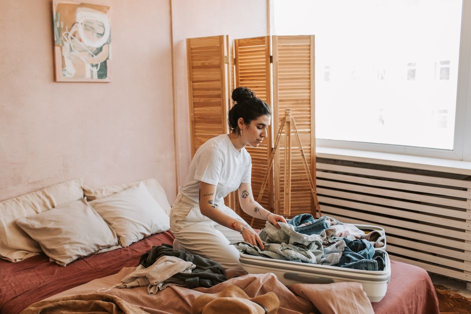 Woman packing suitcase in a cozy bedroom, preparing for travel. Relaxed and intimate setting.