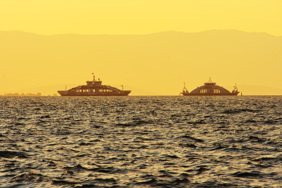 Two ferries sailing in Izmir Bay during a golden sunset, capturing a tranquil seascape.
