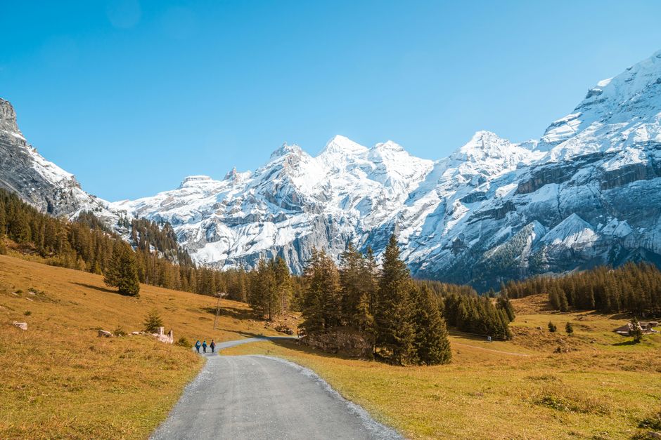 Majestic snowy mountains with a clear blue sky and rural road.