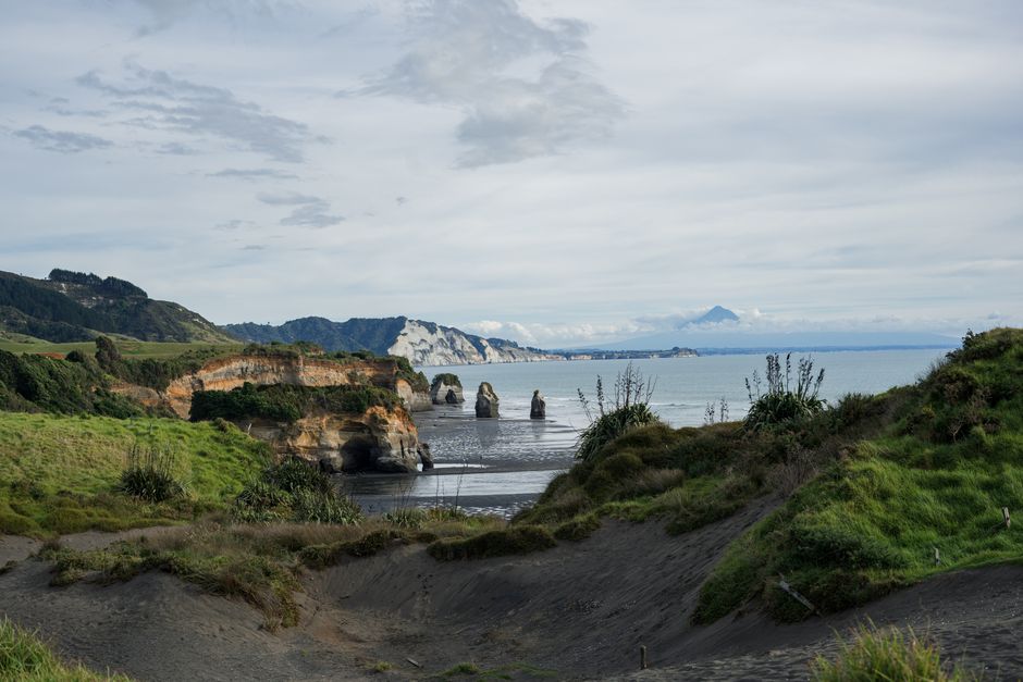 Serene landscape of New Zealand's Elephant Rock and Three Sisters with Mount Taranaki in the background.