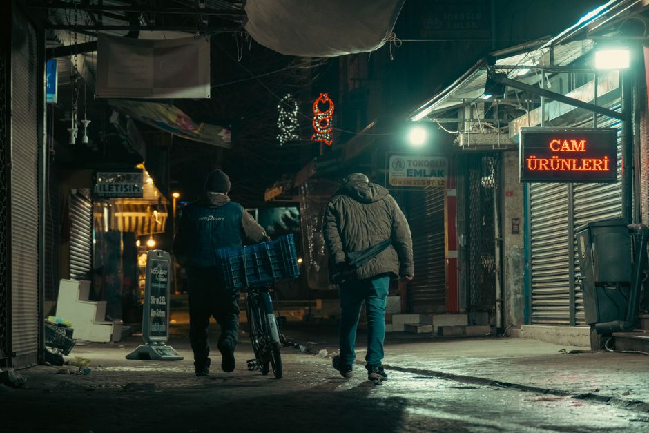 Two people walking on a dimly lit urban street at night.