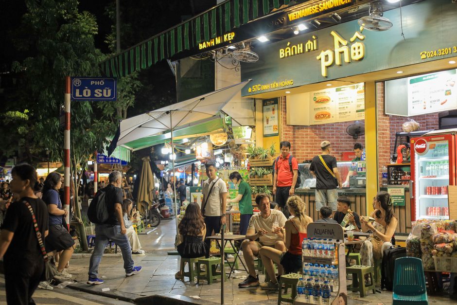 Vibrant night scene of people enjoying street food outside a Vietnamese sandwich shop in H