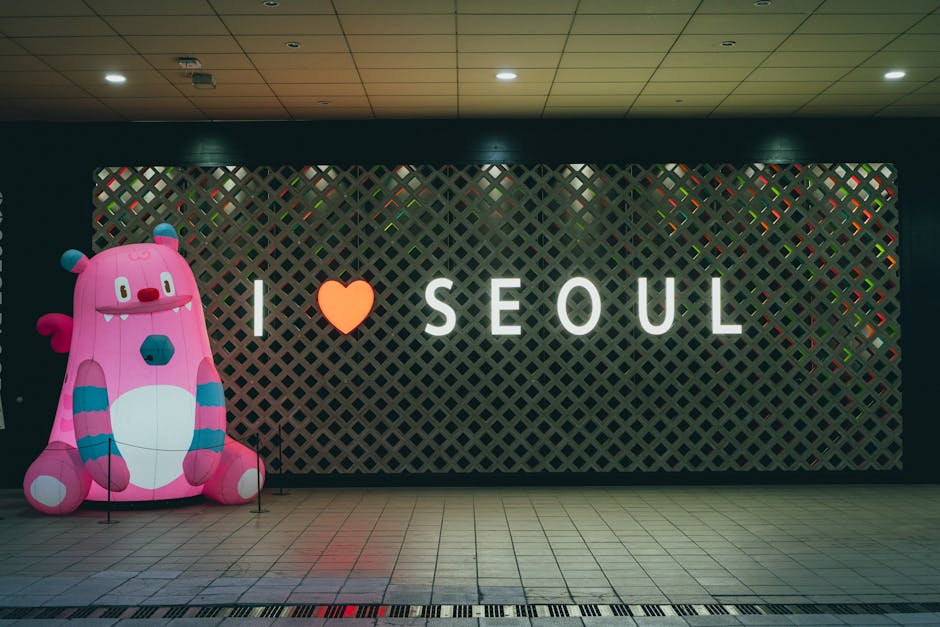A vibrant and playful display featuring an 'I Love Seoul' sign with a pink inflatable character indoors.